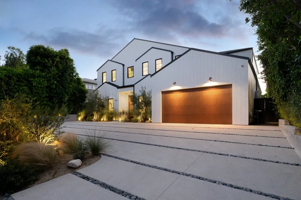 Modern farmhouse with wood garage door at dusk